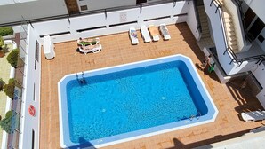 En pool på taket med ett klart, blått vatten, omgiven av solstolar och en liten uteplats.