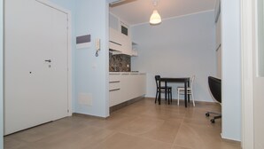 Une cuisine compacte avec un coin repas, une porte blanche et un luminaire suspendu.