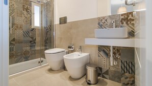 Une salle de bain moderne avec une douche à parois de verre, un bidet, des toilettes et un lavabo avec un miroir au-dessus.