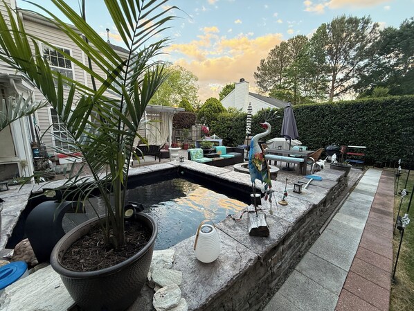 A backyard with a swimming pool, outdoor furniture, a bird sculpture, and a potted plant.