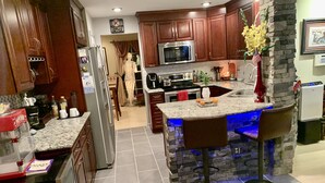 A modern kitchen with dark wooden cabinets, a granite countertop, a built-in microwave, and a stone accent wall. - 2,300 Sqft 2 Story Home With 3 Bedrooms 21/2 Bathrooms in Apex North Carolina (Apex)
