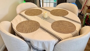A dining table with a woven table runner, surrounded by four cushioned chairs.