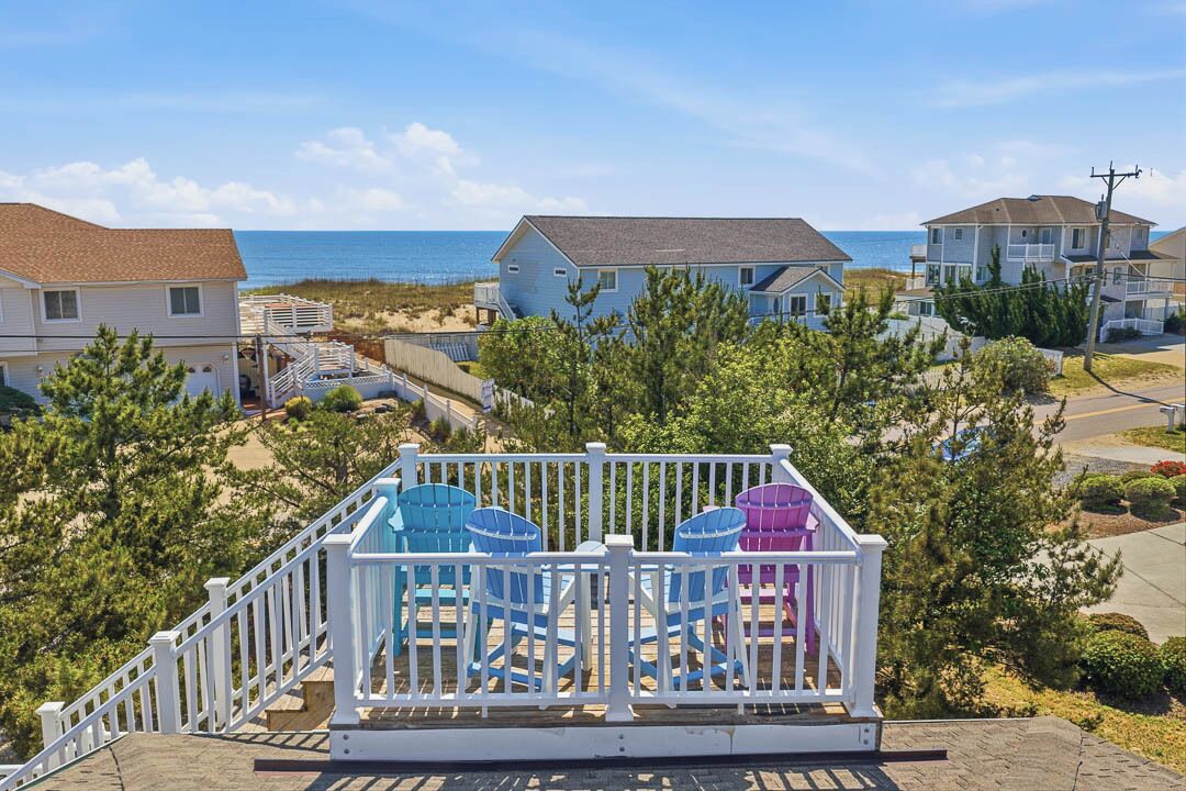 A residential area with houses, a white fence, and chairs.