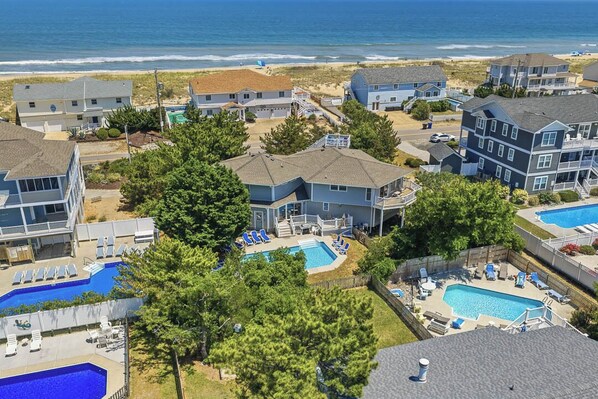 A residential area with multiple houses, a swimming pool, and a beach view.