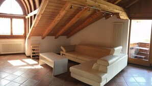 Un loft spacieux avec un plafond haut, un canapé blanc, une petite table et un meuble à bouteilles.