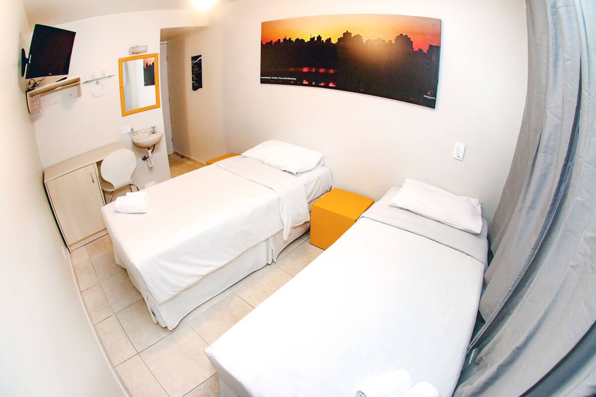 A hotel room with two beds, a bathroom, a TV, and a cityscape view.