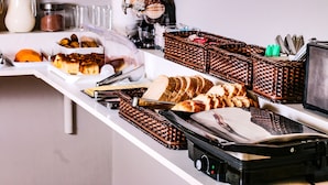 En buffet med forskelligt mad, blandt andet brød, kager og en kaffemaskine.