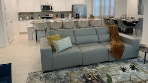 Una cocina moderna con armarios blancos, una isla central y un comedor con mesa y sillas.