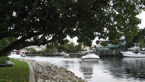 A waterfront area with a stone walkway, boats docked at a pier, and a tree providing shade. - Riverside villa next to Down Town Ft Lauderdale (Fort Lauderdale)