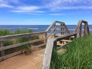 A wooden boardwalk leading to a beach with a clear view of the ocean. - Modern Vacation Home With A/C & Screened In Room. Close To National Park Beach (Brackley Beach)
