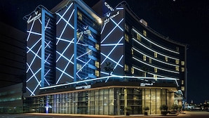 Een hotel met een binnentuin, modern van ontwerp, met verlichte geometrische patronen op de gevel en grote raampartijen.