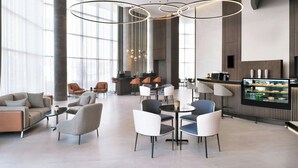 Een moderne lounge met zitplaatsen, een balie en een gekoelde displaykast.