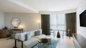 Une chambre d’hôtel moderne équipée d’un canapé, d’une table basse ronde, d’une table à manger et d’un téléviseur.