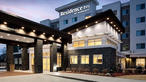 Una entrada de hotel moderna con un letrero claro que dice “Residence Inn by Marriott” y un cartel de autorización visible.
