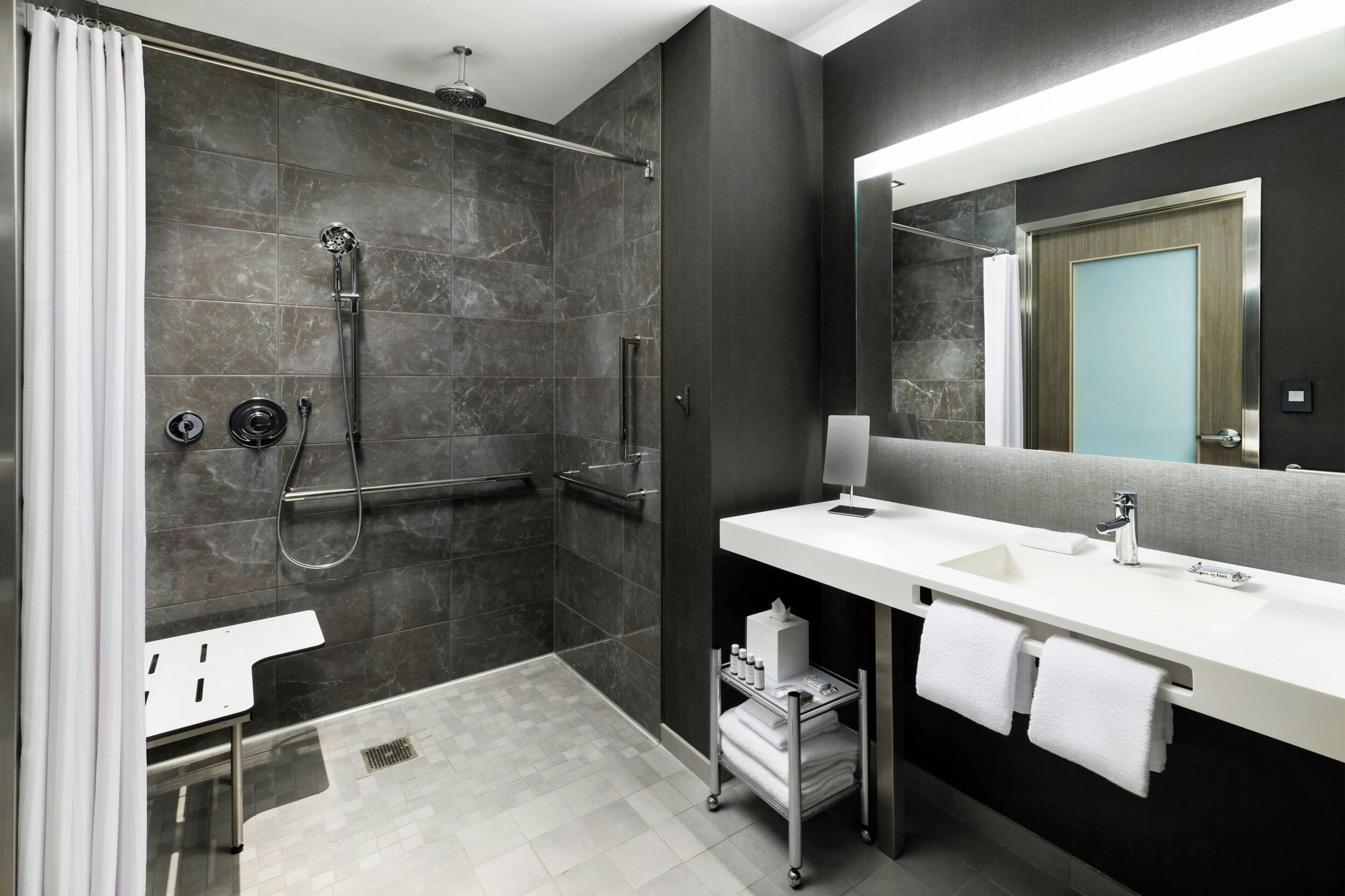 Une salle de bain moderne avec une douche, un lavabo et un miroir.