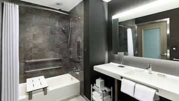 A modern bathroom with a bathtub, shower, vanity, and a large mirror.
