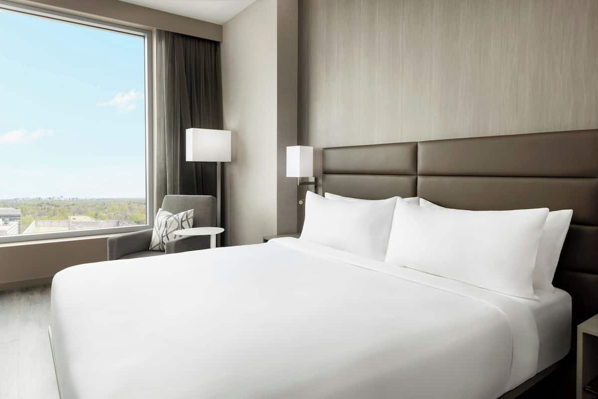 Een hotelkamer met een groot bed, uitzicht op de stad, een bureau en een stoel.