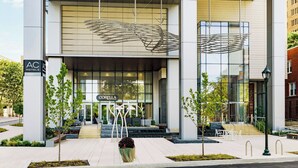 A hotel entrance with a modern design, featuring a large glass facade, a distinctive wing-like sculpture above the entrance, and a sign for the Corella hotel. - AC Hotel by Marriott Bethesda Downtown (Bethesda)