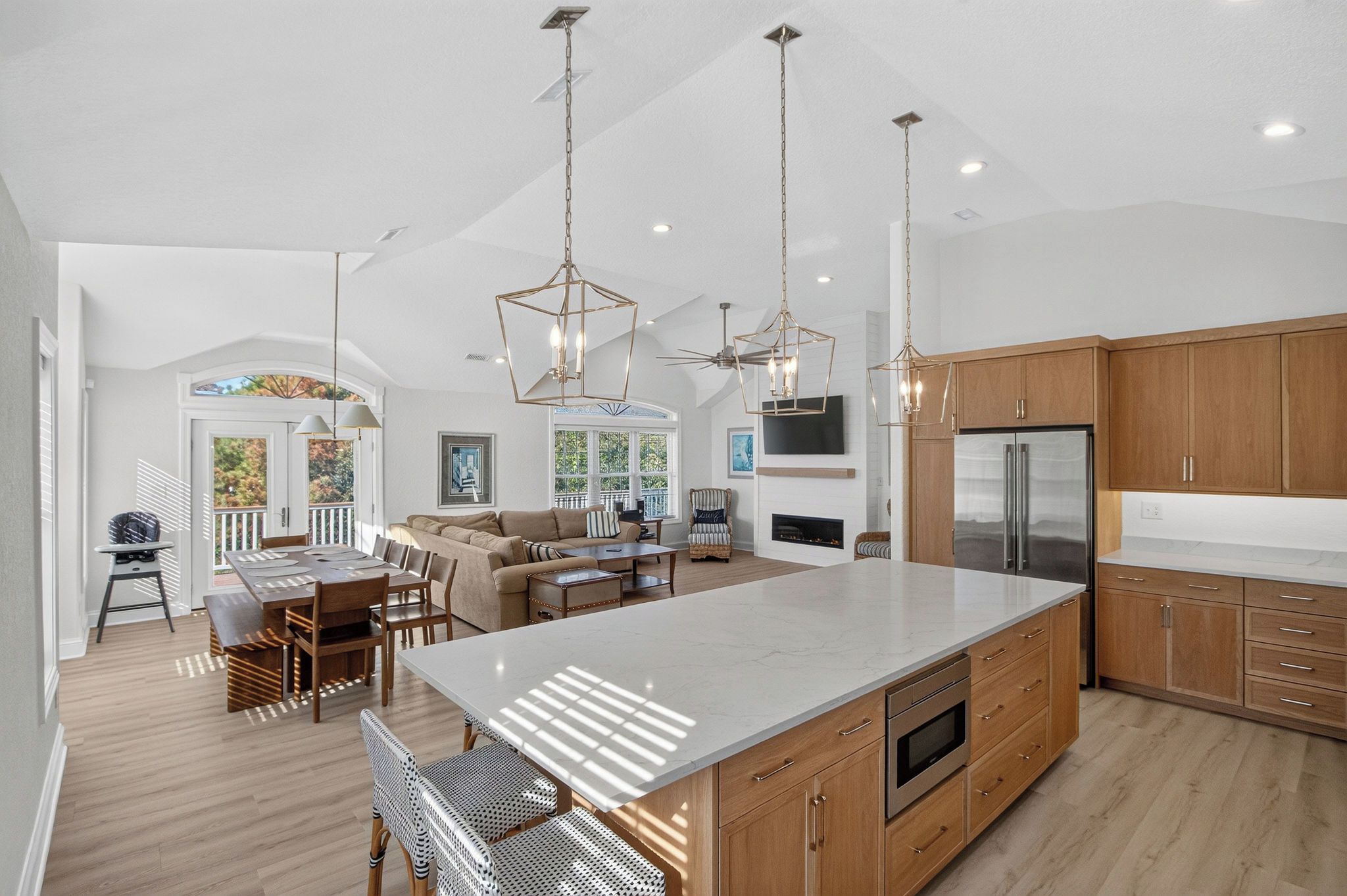 A spacious kitchen with a large island, wooden cabinets, and modern pendant lighting.