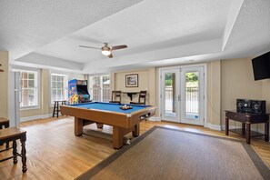 A pool table in a room with a ceiling fan, a pool table, and a television on a stand. - Renovated! Gorgeous Views, Private Pool, Hot Tub, close to Beach, SS0028 (Southern Shores)