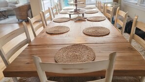 Un tavolo da pranzo in legno con sottopiatti intrecciati e sedie bianche.