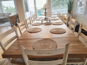 A wooden dining table with woven placemats and white chairs.