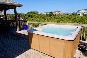 Eine Holzterrasse mit Whirlpool, einem blauen Eimer und einer amerikanischen Flagge.