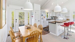 Une cuisine spacieuse avec des meubles blancs, une table à manger en bois et des tabourets de bar rouges.