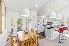 A spacious kitchen with white cabinetry, a wooden dining table, and red bar stools.