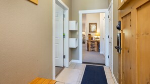 A hallway with a wooden bench, a door with a handle, a wall-mounted light fixture, and a doorbell. - On Keystone Lake/Shared Hot Tub/Quick Shuttle Ride to the Lifts (Keystone)