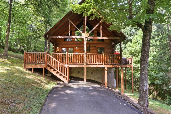 A wooden cabin with a balcony, surrounded by trees. - Great Smokies Adventure Cabin w/Hot Tub and Deck! (Sevierville)