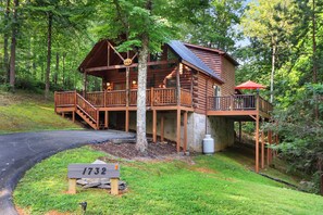 A wooden cabin with a porch, surrounded by trees. - Great Smokies Adventure Cabin w/Hot Tub and Deck! (Sevierville)