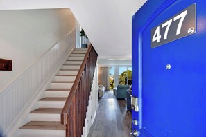 Una escalera lleva a un rellano con una puerta azul marcada con el número 477.