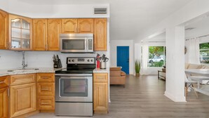 Une cuisine moderne avec des meubles en bois, des appareils en acier inoxydable et une vue sur l’espace de vie.