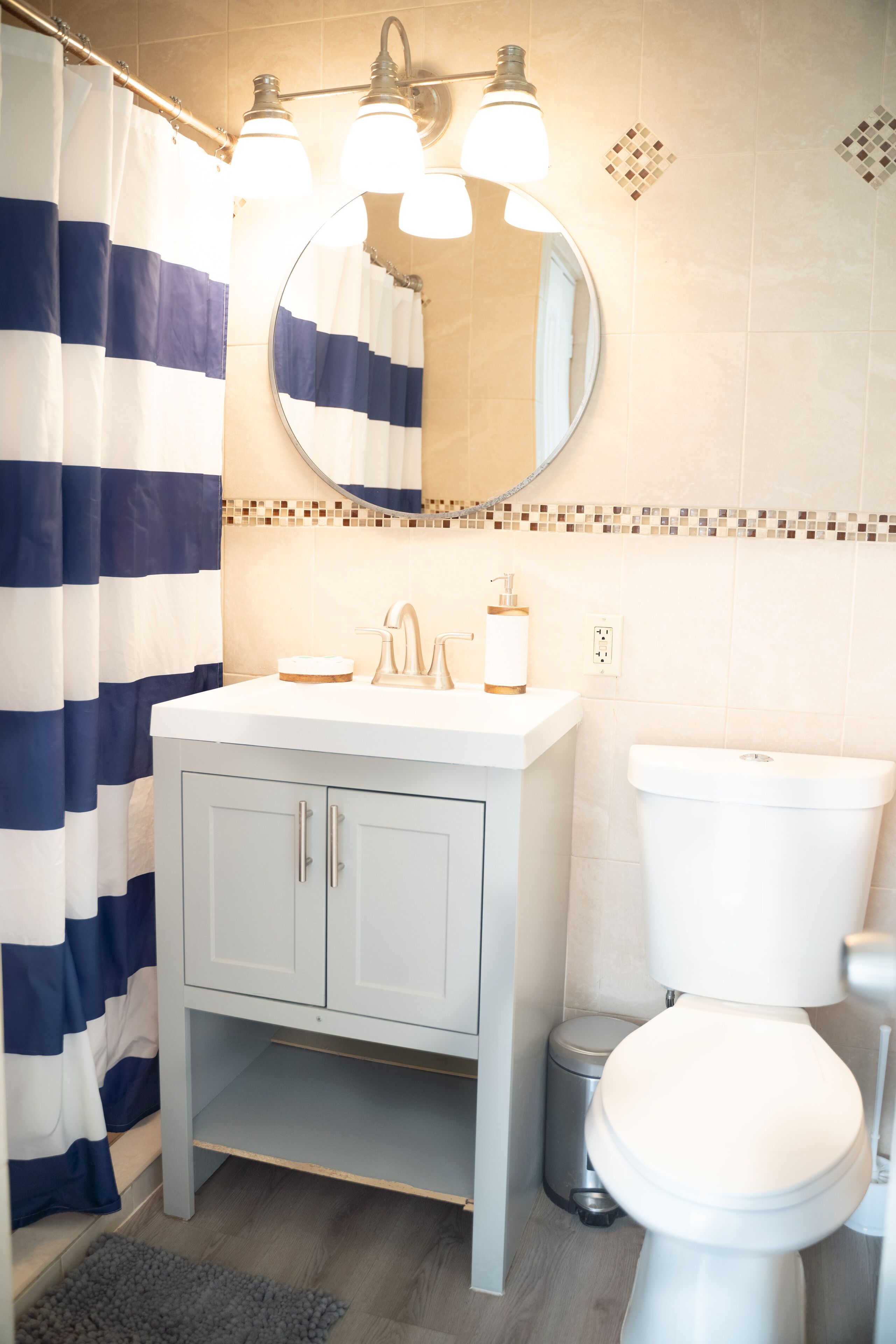 Een badkamer met een witte wastafel, een spiegel erboven, een toilet en een douchegordijn.