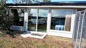 A house with a large sliding glass door leading to a deck, surrounded by a chain-link fence.