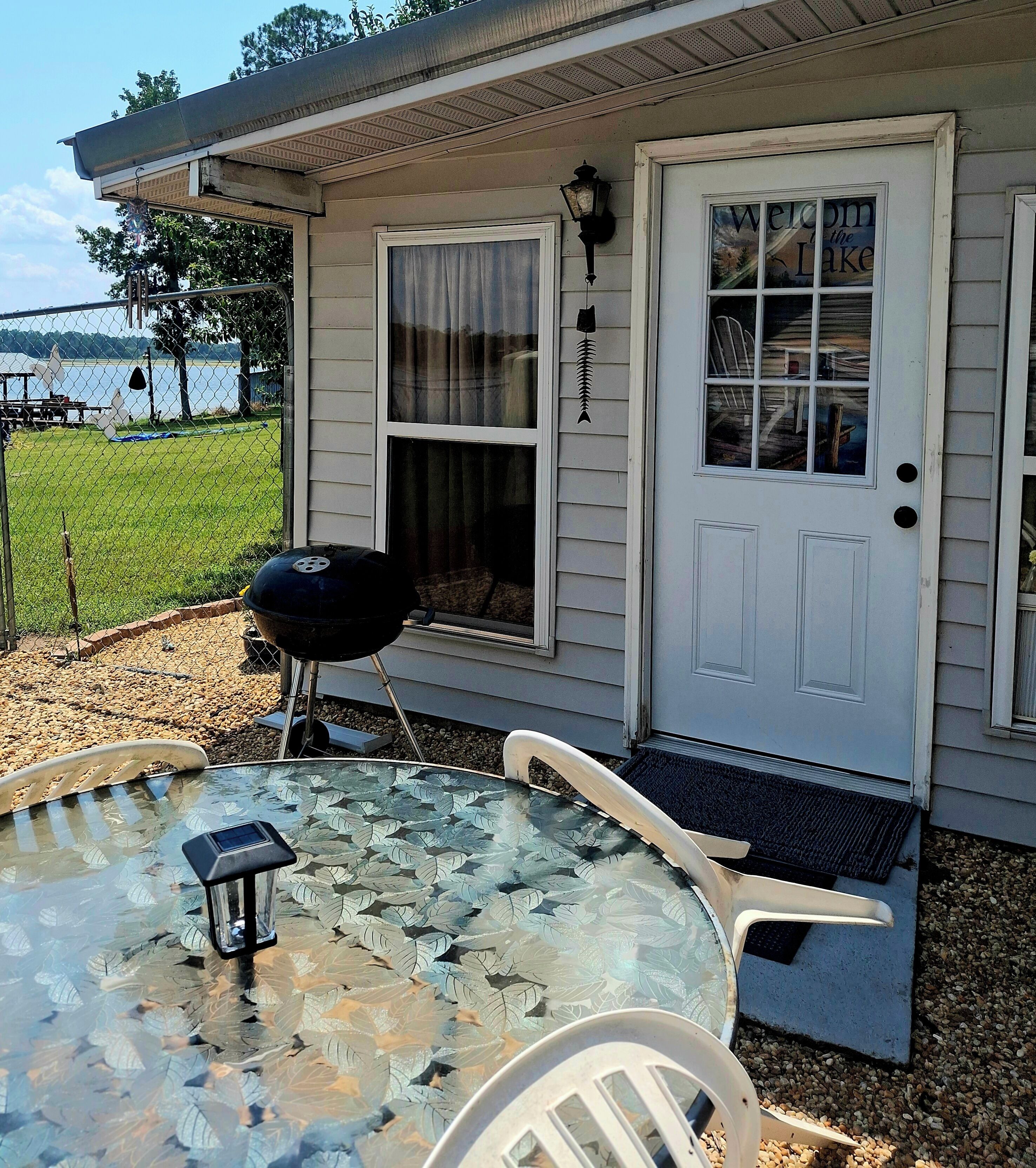 A house with a covered patio, a barbecue grill, and a glass table with chairs.