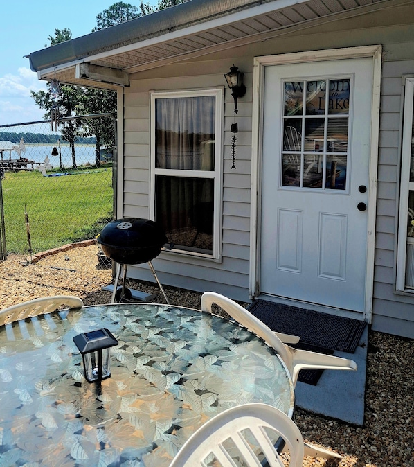 A house with a covered patio, a barbecue grill, and a glass table with chairs.