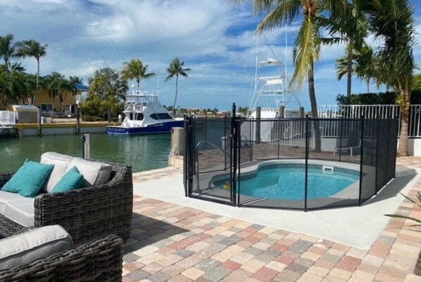 Enjoy a pool area with a marina view, surrounded by a safety fence and a wicker lounge chair.