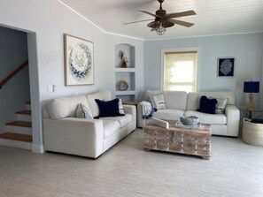 Relax in this stylish living room with a high ceiling, ceiling fan, and large window.