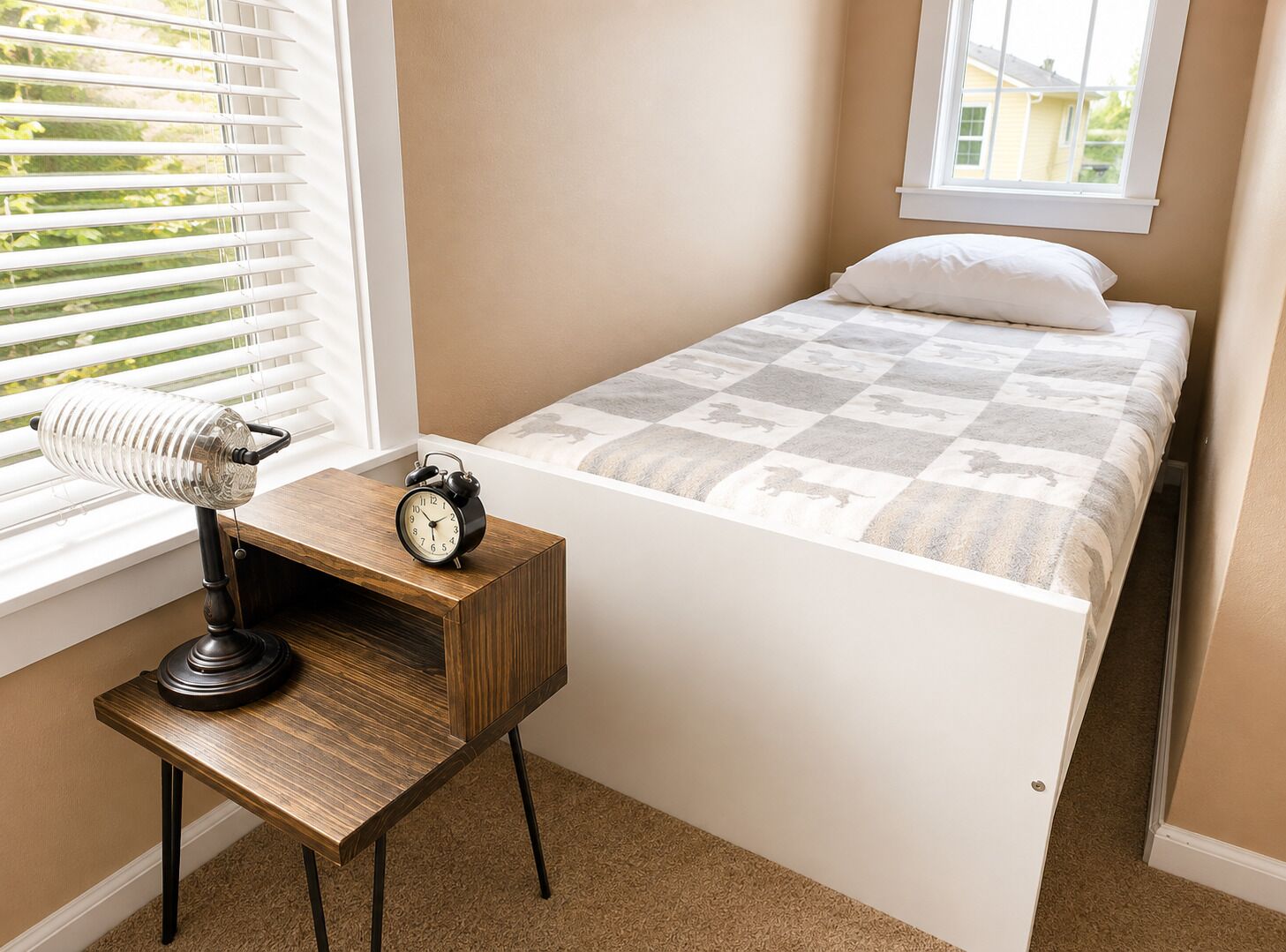 Un dormitorio con una cama, una mesita de noche con lámpara y una ventana con persianas.