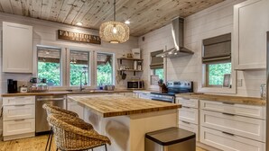 A modern kitchen with white cabinetry, a wooden island, and a farmhouse sign.