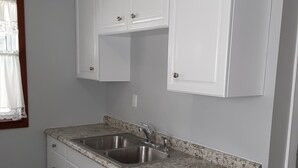 Cuina amb armaris blancs, tauleig de granit i una aixeta d'acer inoxidable.