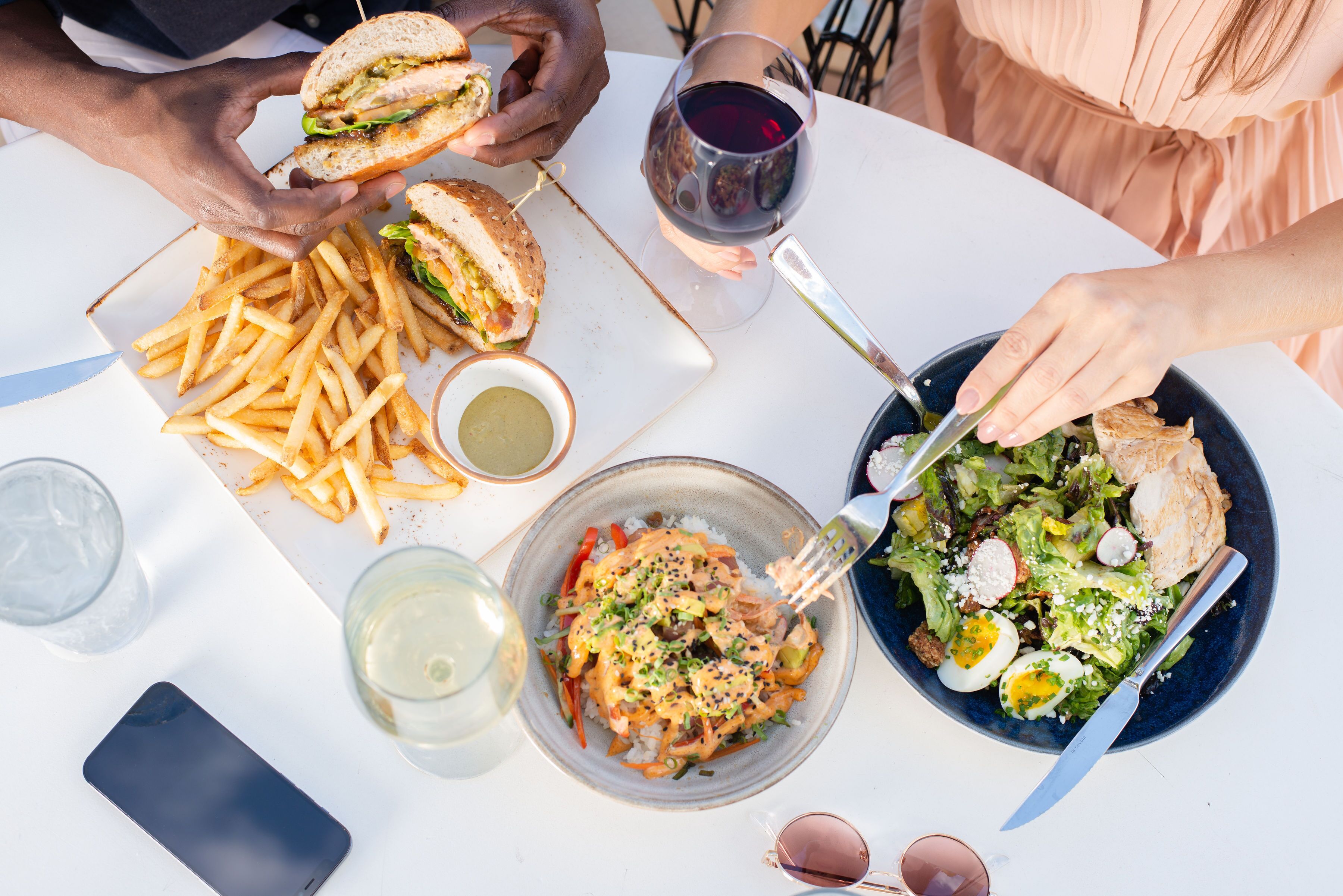 A table with a sandwich, fries, salad, and drinks.