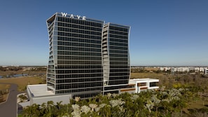 Un hotel moderno con un llamativo letrero 'WAVE' en la parte superior, que presenta una fachada con diseño de cuadrícula y un techo plano.
