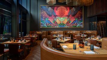A restaurant with multiple seating areas, including booths and tables, and a large mural on the wall.