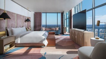 Une chambre d’hôtel moderne dotée d’un grand lit, d’un canapé, d’une télévision et offrant une vue sur la ville.