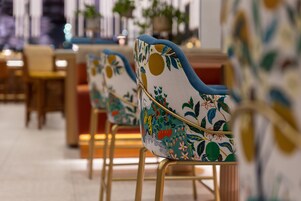 Una fila di sedie con rivestimenti floreali e gambe dorate in una sala da pranzo.