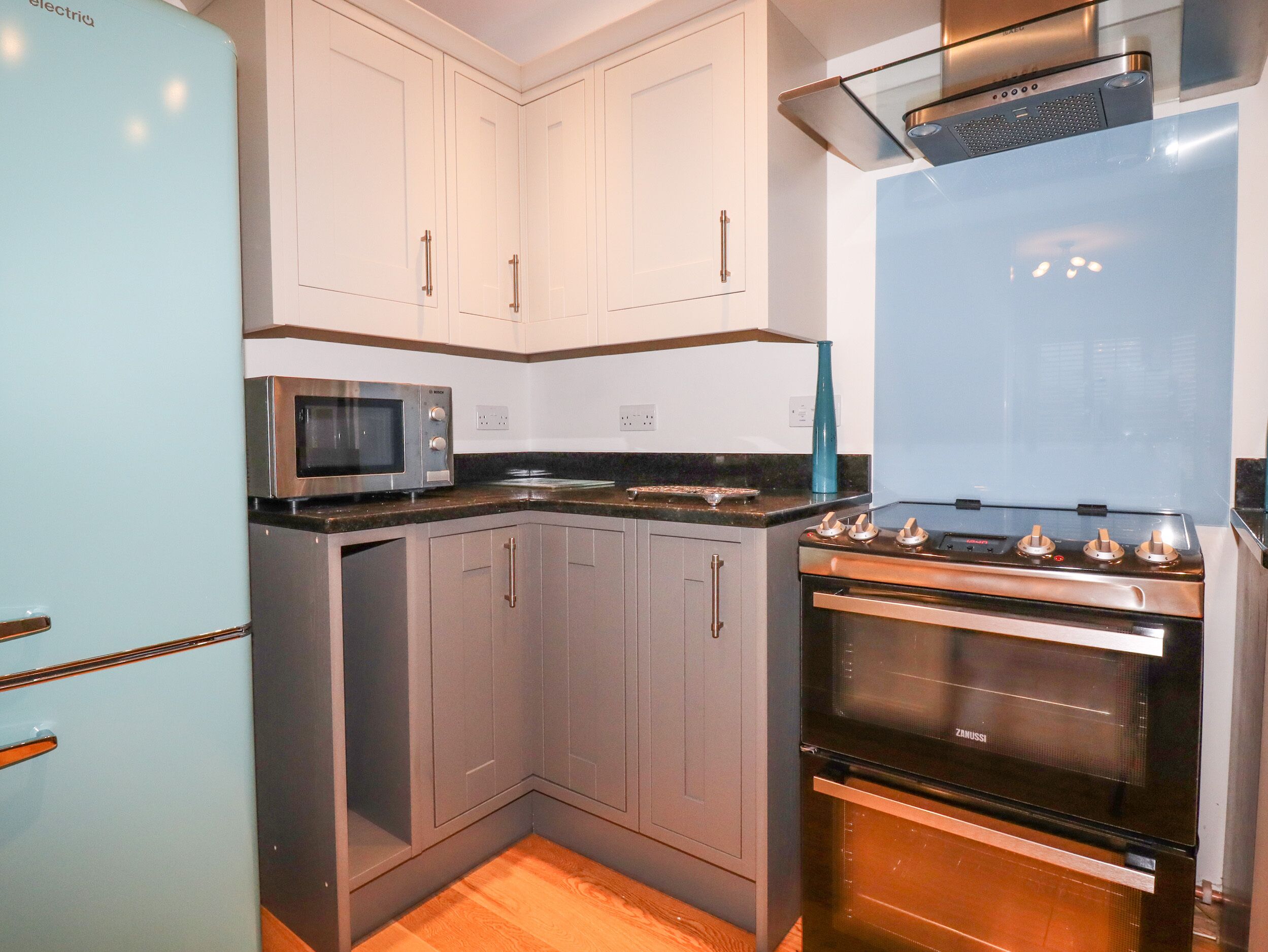 A modern kitchen with grey cabinets, a stainless steel stove, and a microwave.