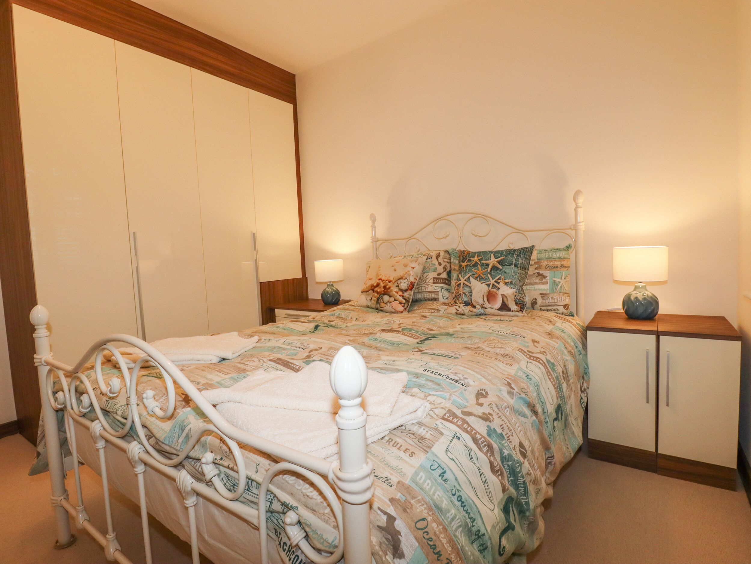 A bedroom with a bed, nightstands, a wardrobe, and a decorative headboard.
